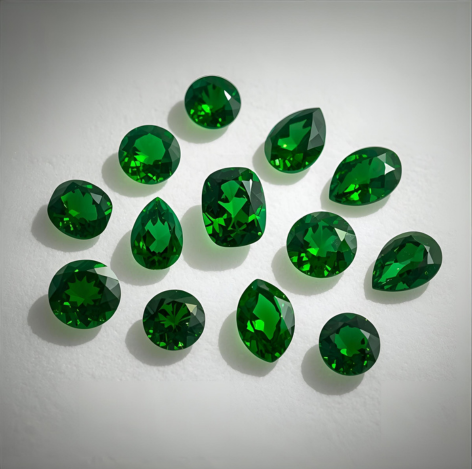 Faceted Tsavorite Garnet gemstones in different cuts displayed on white velvet.